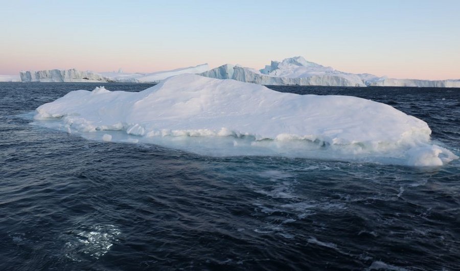 Iceberg in the Icefjord at Ilulissat off the west coast of Greenland. The light in the water on the left is the underwater robot.